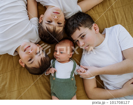 Three big brothers with their little newborn brother lying in bed. Three big brothers with their little newborn brother lying in bed. 101708127