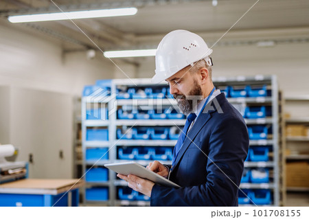 Manager in suit controlling goods in a warehouse. 101708155