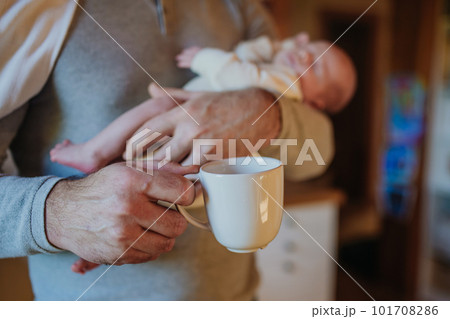 Close- up of father holding her newborn baby and cup of coffee. 101708286