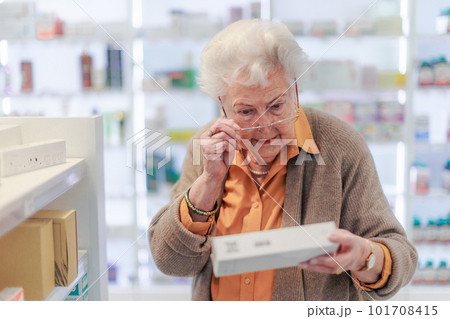 Senior woman reading text on the medication box. 101708415