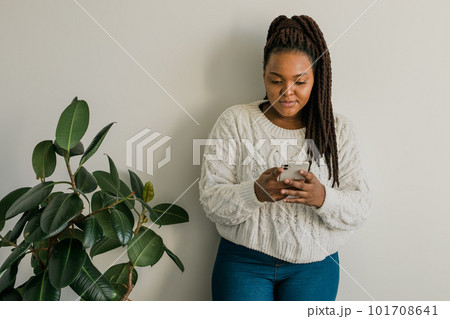 Portrait of African American female student dressed casually holding mobile phone and typing messages and communicating with friends via social networks using high-Internet connection. Portrait of African American female student dressed casually holding mobile phone and typing messages and communicating with friends via social networks using high-Internet connection. 101708641