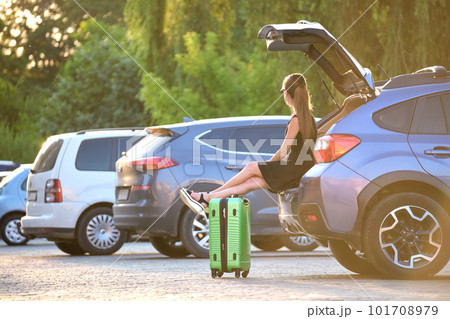 Young woman with suitcase bag waiting near her car. Travelling and vacations concept Young woman with suitcase bag waiting near her car. Travelling and vacations concept 101708979
