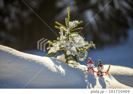 Two small funny toys baby snowman in knitted hats and scarves in deep snow outdoors near pine tree branch. Happy New Year and Merry Christmas greeting card. Two small funny toys baby snowman in knitted hats and scarves in deep snow outdoors near pine tree branch. Happy New Year and Merry Christmas greeting card. 101710409