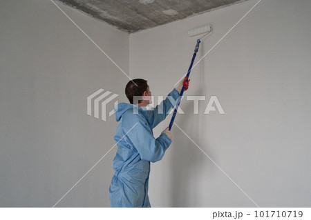 Man paints the ceiling with a roller 101710719