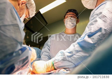 Surgeon face in operating room, stressful operation, surgeon performs operation in modern operating room with activity life support devices and light lamps, life saving, inoperable sarcoma. Surgeon face in operating room, stressful operation, surgeon performs operation in modern operating room with activity life support devices and light lamps, life saving, inoperable sarcoma. 101711630