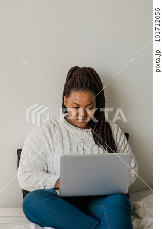 African american young woman using laptop on bed - technologies and communication and social network concept African american young woman using laptop on bed - technologies and communication and social network concept 101712056