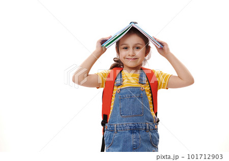 Caucasian smart student child girl,positive pleasant first grader holding open book above her head, smiling cutely looking at camera, isolated over white background. Back to school. Education concept Caucasian smart student child girl,positive pleasant first grader holding open book above her head, smiling cutely looking at camera, isolated over white background. Back to school. Education concept 101712903