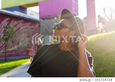 African american woman in an urban city area. Smiling generation z or millennial hipster girl posing outdoor backlit with sunlight portrait 101714738