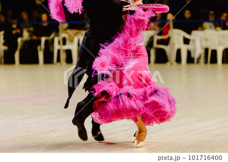 couple dancing foxtrot in competitive ballroom dancesport, woman is wearing pink dress and man black tail suit 101716400