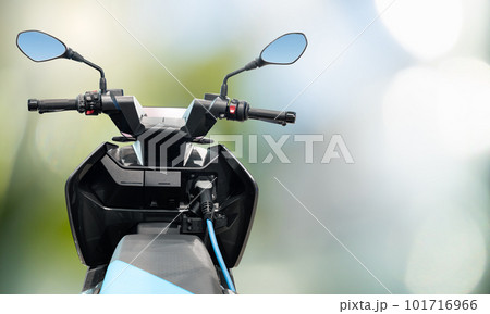 Electric scooter with connected charging cable on a green background Electric scooter with connected charging cable on a green background 101716966