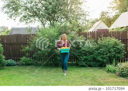 Organic female farmer holding box full of fresh produce on her farm copyspace. Happy young woman smiling at camera while standing in her vegetable garden. Successful female farmer harvesting Organic female farmer holding box full of fresh produce on her farm copyspace. Happy young woman smiling at camera while standing in her vegetable garden. Successful female farmer harvesting 101717094