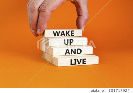Wake up and live symbol. Concept words Wake up and live on wooden blocks. Beautiful orange table orange background. Businessman hand. Business lifestyle wake up and live concept. Copy space. Wake up and live symbol. Concept words Wake up and live on wooden blocks. Beautiful orange table orange background. Businessman hand. Business lifestyle wake up and live concept. Copy space. 101717924