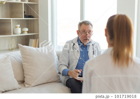 Senior man doctor examining yound woman in doctor office or at home. Girl patient and doctor have consultation in hospital room. Medicine healthcare medical checkup. Visit to doctor Senior man doctor examining yound woman in doctor office or at home. Girl patient and doctor have consultation in hospital room. Medicine healthcare medical checkup. Visit to doctor 101719018