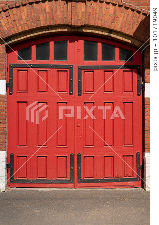 A red wooden portal for several cars. Old Fire station. arch and window with metal decorations. A red wooden portal for several cars. Old Fire station. arch and window with metal decorations. 101719049