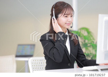 ヘッドセットに手を当て話を聞く女性オペレーター1 ヘッドセットに手を当て話を聞く女性オペレーター1 101719237