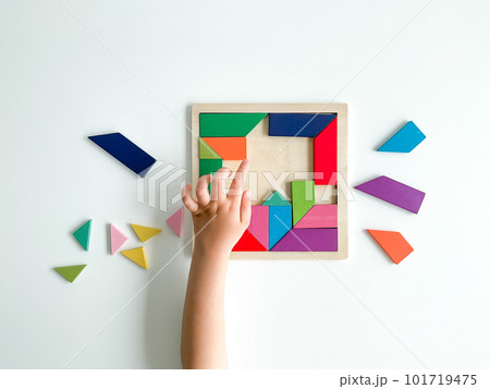 childs hand collects multicolored wooden mosaic on white background. 101719475