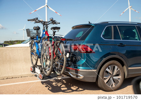 Back view modern white family wagon car with mounted roof box trunk and bike tail carrier driving european highway road against blue sky summer day. Lifestyle travel adventure trip journey concept Back view modern white family wagon car with mounted roof box trunk and bike tail carrier driving european highway road against blue sky summer day. Lifestyle travel adventure trip journey concept 101719570