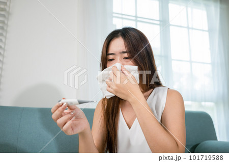 Sick woman have symptom sick high fever she checking her temperature with thermometer in living room at home, young female suffering from flu cold and fever, health care and medical concept 101719588