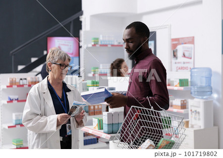 African american client discussing with pharmacist asking for help with cardiology drugs, worker explaining medical leaflet. Drugstore employee offering support assistance, medicine service African american client discussing with pharmacist asking for help with cardiology drugs, worker explaining medical leaflet. Drugstore employee offering support assistance, medicine service 101719802