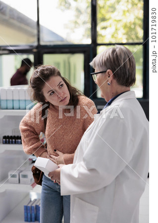 Drugstore worker helping sick adult client with abdominal cramps offering stomachache medication while working in pharmacy. Customer having gastritis looking for pills to cure food poisoning Drugstore worker helping sick adult client with abdominal cramps offering stomachache medication while working in pharmacy. Customer having gastritis looking for pills to cure food poisoning 101719830