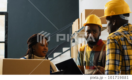 Male workers planning shipment with laptop in depot space, checking boxes with merchandise before doing distribution. Two men doing quality control in storage room, cargo stock. 101719881