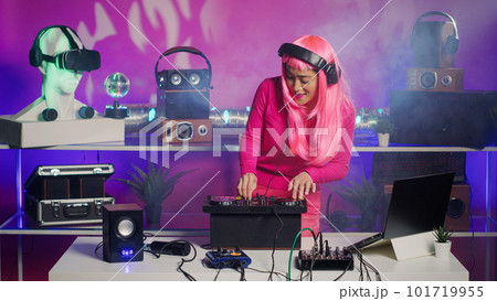 Cheerful dj mixing and mastering electronic sound using professional turntables, enjoying performing music during night party in club. Asian artist doing performance with audio equipment Cheerful dj mixing and mastering electronic sound using professional turntables, enjoying performing music during night party in club. Asian artist doing performance with audio equipment 101719955