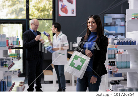 Satisfied pharmacy store client holding prescription medicine purchase bag and looking at camera. Smiling happy buyer holding drugstore paper package with medicaments portrait 101720354