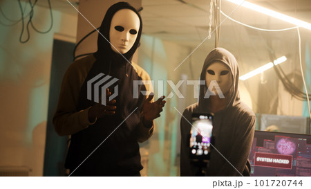Team of anonymous thieves broadcasting threat video, asking for passwords ransomware instead of leaking data. Hackers with masks threatening to expose government information. Handheld shot. 101720744