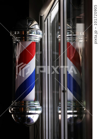 Barber pole spinning at night. International barbershop pole sign. A barber pole calling for people at street. Vintage barbershop. Salon. Barber pole spinning at night. International barbershop pole sign. A barber pole calling for people at street. Vintage barbershop. Salon. 101720905