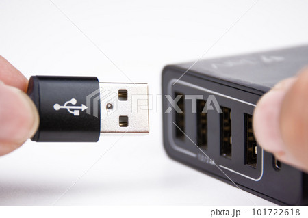 USB A charging cable in hand is plugging into a multi port mobile phone charger. USB A charging cable in hand is plugging into a multi port mobile phone charger. 101722618