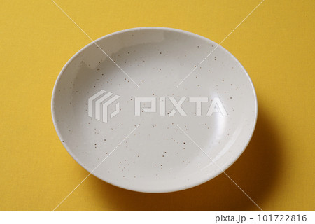 黄色い背景に置かれた梨地の皿 101722816