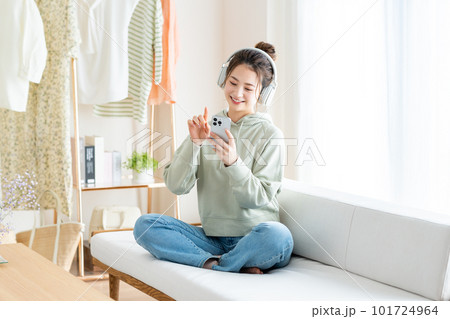 リビングで音楽を聴く若い女性 リビングで音楽を聴く若い女性 101724964