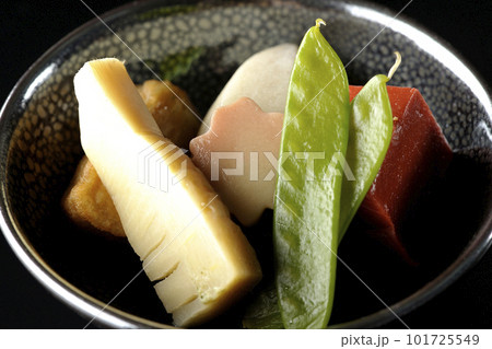 筍や里芋、生麩、サヤエンドウ等が入っている煮物を黒背景で撮影 101725549
