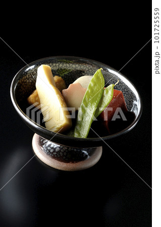 筍や里芋、生麩、サヤエンドウ等が入っている煮物を黒背景で撮影 101725559