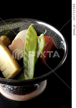 筍や里芋、生麩、サヤエンドウ等が入っている煮物を黒背景で撮影 101725568