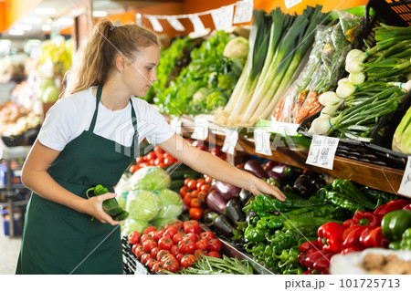 Focused girl who works part-time as a trainee saleswoman puts pepper on showcase Focused girl who works part-time as a trainee saleswoman puts pepper on showcase 101725713