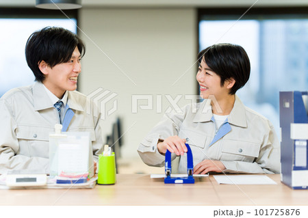 穴あけパンチをする作業服を着た男女 101725876