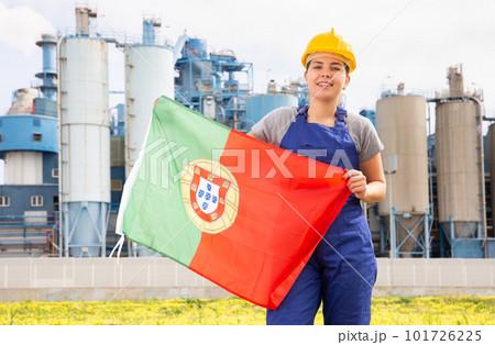 Young female engineer in helmet waving state flag of Portugal while standing in front of big tanks at chemical plant Young female engineer in helmet waving state flag of Portugal while standing in front of big tanks at chemical plant 101726225