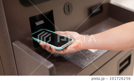 Woman using smartphone online financial transactions at ATM. NFC online banking concept. Woman using smartphone online financial transactions at ATM. NFC online banking concept. 101726256