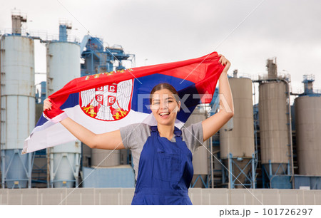 Smiling young woman near factory with flag of Serbia Smiling young woman near factory with flag of Serbia 101726297