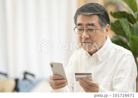 クレジットカードを使いネットショッピングするシニア男性 101726671