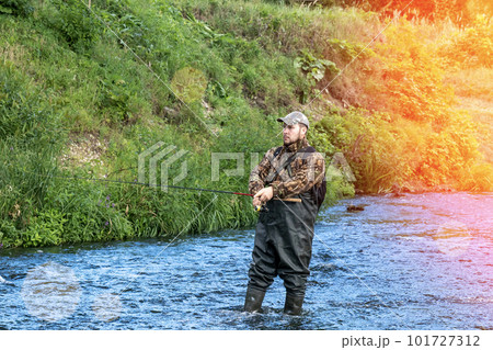 A fisherman catches fish while standing in the water 101727312
