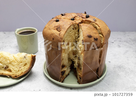 Panettone Italian Sweet Cake, Cut Piece And Cup Of Coffee On Table And Cut Piece. Sweet bread, Fruitcake Originally From Italy, Milan Baked Dessert. Closeup. Horizontal plane. 101727359