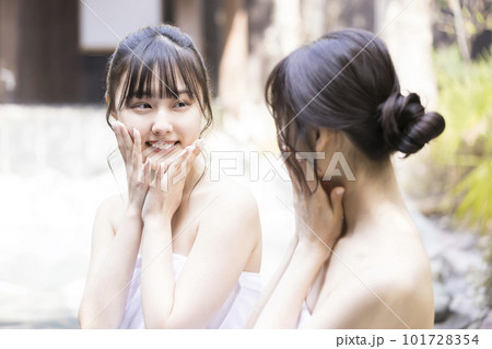 温泉に入って肌の潤いを確かめる若い女性2人 101728354