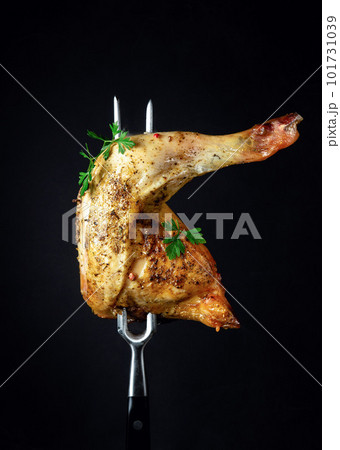 Baked chicken thigh with parsley on a fork. Menu or recipe concept for restaurant or hotel on black background. Baked chicken thigh with parsley on a fork. Menu or recipe concept for restaurant or hotel on black background. 101731039