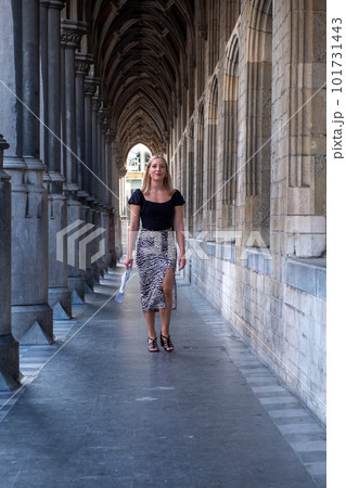 Beautiful young blonde woman wearing stylish business attire and high heels walking inside a covered Beautiful young blonde woman wearing stylish business attire and high heels walking inside a covered 101731443