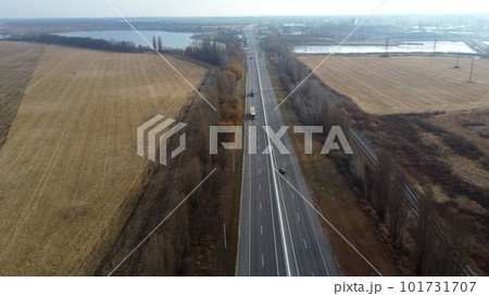 Landscape Highway, driving cars, agricultural fields after harvest, lakes on autumn day. Flying over automobile asphalt road with white markings and many cars. Perspective scenery. Aerial drone view Landscape Highway, driving cars, agricultural fields after harvest, lakes on autumn day. Flying over automobile asphalt road with white markings and many cars. Perspective scenery. Aerial drone view 101731707