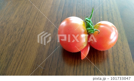 木のテーブルの上の赤い双子トマト 101733047
