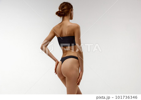 Young girl, model with slim, sportive, fit body, buttocks posing in underwear against white studio background. Anti-cellulite care Young girl, model with slim, sportive, fit body, buttocks posing in underwear against white studio background. Anti-cellulite care 101736346