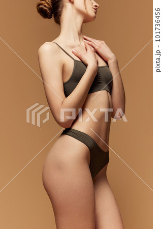 Fit and healthy. Cropped Image of slim female body in cotton underwear posing against light brown studio background Fit and healthy. Cropped Image of slim female body in cotton underwear posing against light brown studio background 101736456